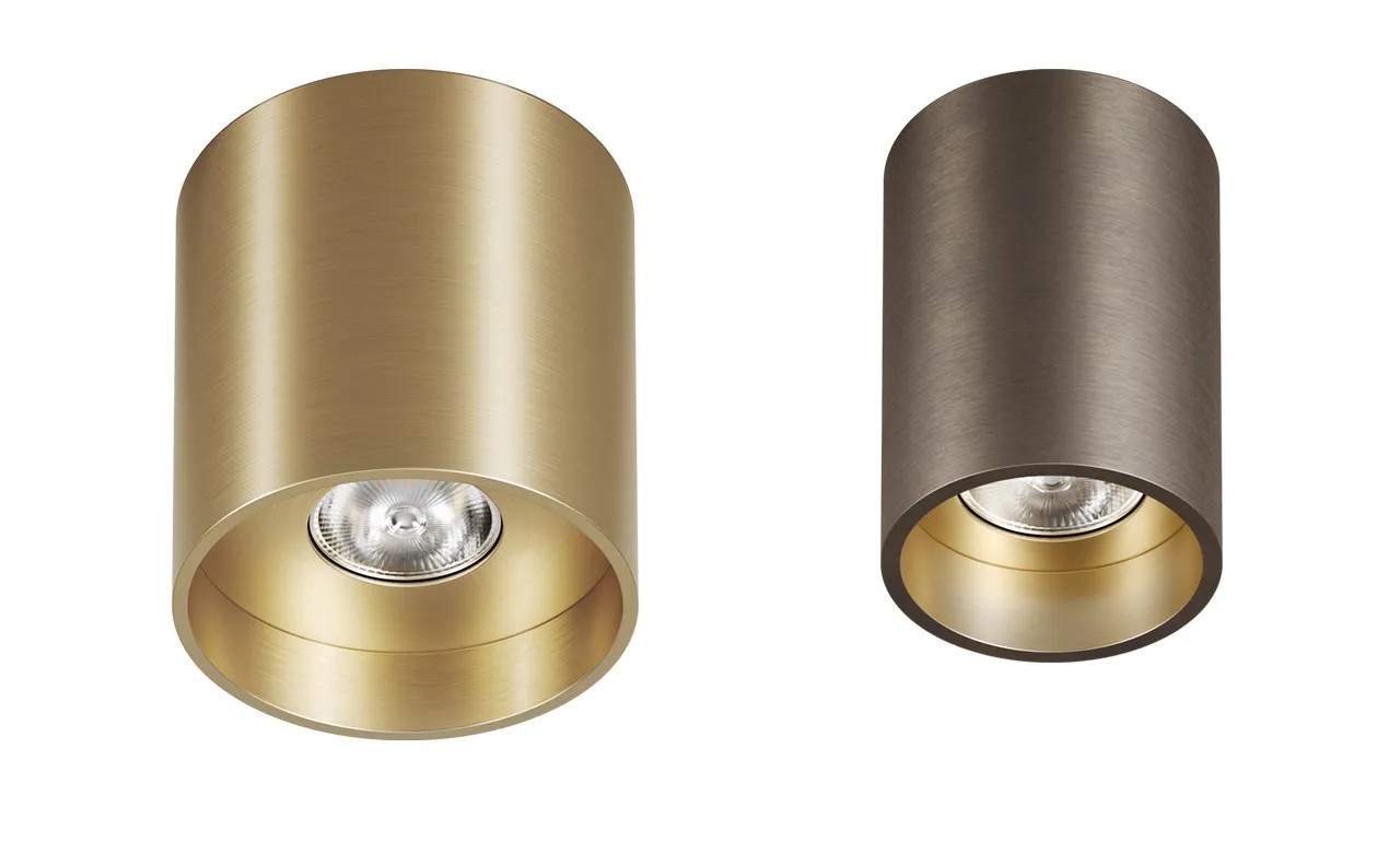 Produktrendering: zwei zylindrische Aufbau-Downlights in Messing und Bronze